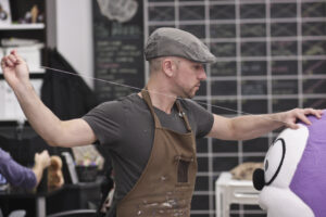 Image of a mascot designer hand sewing part of a mascot head